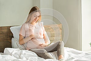 Young preganant woman expecting a baby relaxing on bed indoors