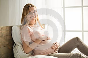 Young preganant woman expecting a baby relaxing on bed indoors