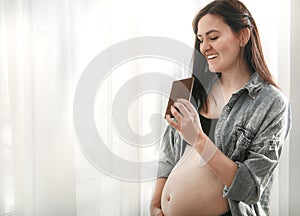 Young pregnant cheerful beautiful woman eating chocolate