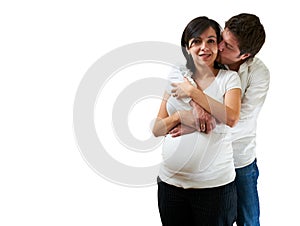 Young pregnant couple hugging on white background