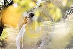 Young pregnant couple sitting on yellow leaves in the park