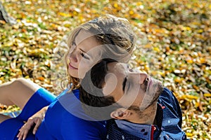 Young pregnant couple sitting on yellow leaves in the park