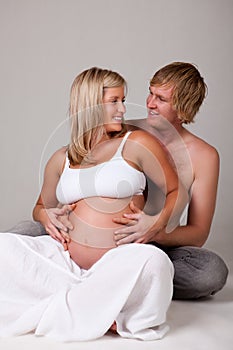 Young Pregnant Couple Smiling At Each Other