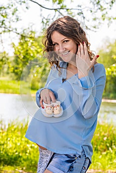 Young pregnant girl in a white sarafan on a plaid in a park