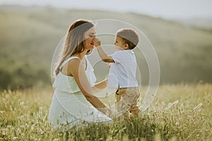 Young pregnant mother with her cute little boy in the field on beautiful sunny day