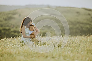 Young pregnant mother with her cute little boy in the field on beautiful sunny day