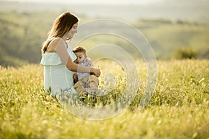 Young pregnant mother with her cute little boy in the field on beautiful sunny day