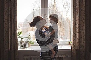 Young pregnant mother and son playing, hugging, kissing the wind