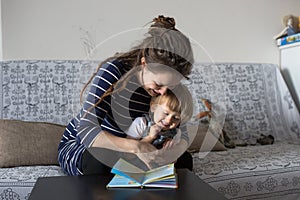 Young pregnant mother and son reading a book, lifestyle,