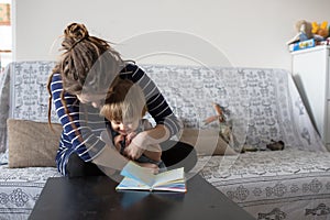 Young pregnant mother and son reading a book, lifestyle,