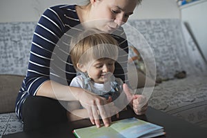 Young pregnant mother and son reading a book, lifestyle,