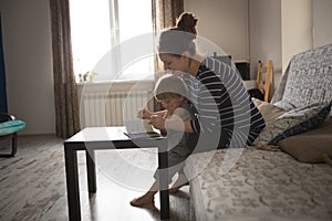Young pregnant mother and son reading a book, lifestyle,
