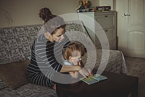 Young pregnant mother and son reading a book, lifestyle,