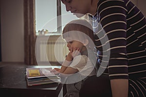 Young pregnant mother and son reading a book, lifestyle,