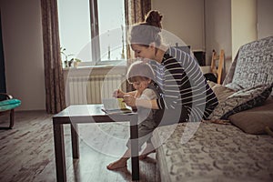 Young pregnant mother and son reading a book, lifestyle,