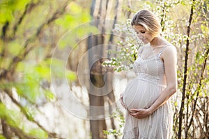 Young pregnant woman against blossoming tree