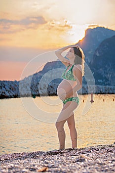 Young pregnant woman on the beach on sunrise