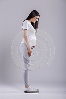 Young pregnant woman checking weight