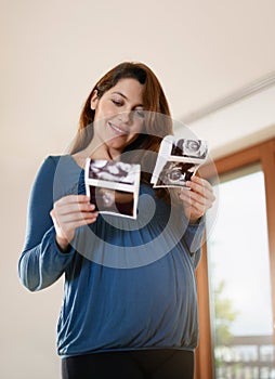 Young Pregnant Woman Comparing Medical Baby Scans