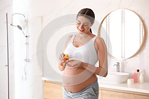 Young pregnant woman with cosmetic product