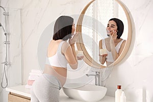 Young pregnant woman with cosmetic product in bathroom