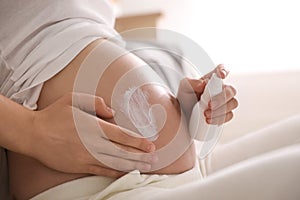 Young pregnant woman with cosmetic product, closeup