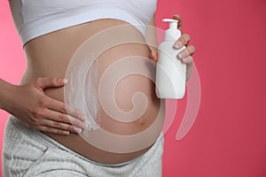 Young pregnant woman with cosmetic product on pink, closeup. Space for text