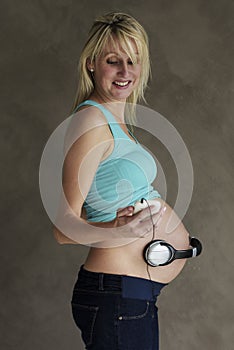 Young pregnant woman dancing to music with her unborn child