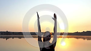 A Young Pregnant Woman Does a Yoga Tree Exercise at a Splendid Sunset