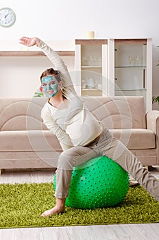 The young pregnant woman doing exercises at home