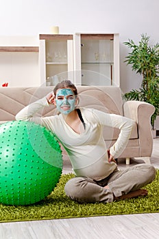 The young pregnant woman doing exercises at home