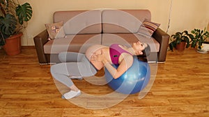 Young pregnant woman doing fitness exercises on a fitness ball. Exercises for pregnant women. Fitness at home. Lift the