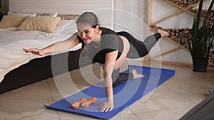 Young pregnant woman doing fitness and yoga exercises on blue mat at home.