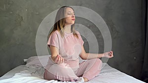 young pregnant woman doing morning yoga exercise after waking up at home. Yogi female model sitting cross-legged on the