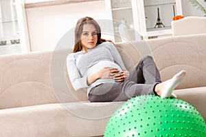 The young pregnant woman doing sport exercises at home