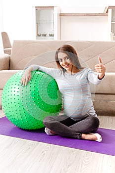 The young pregnant woman doing sport exercises at home