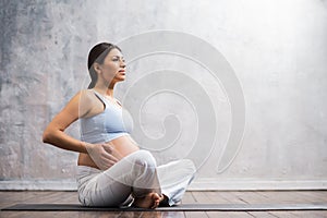 Young pregnant woman doing yoga exercises and meditating at home. Health care, mindfulness, relaxation and wellness