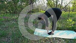 Young pregnant woman doing yoga outside.