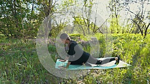 Young pregnant woman doing yoga outside.