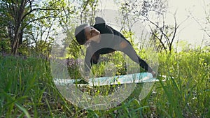 Young pregnant woman doing yoga outside.