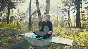 Young pregnant woman doing yoga outside.