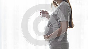 Young pregnant woman drinking water at home, healthcare and pregnancy care concept