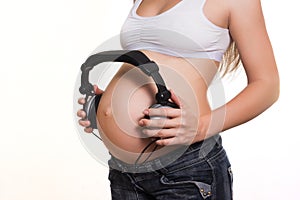 Young pregnant woman with earphones on the belly