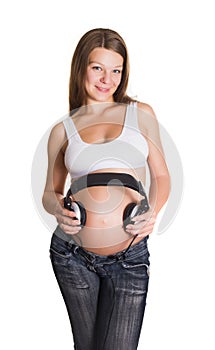 Young pregnant woman with earphones on the belly