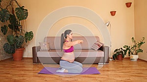 A young pregnant woman is engaged in fitness at home. Exercises for pregnant women. Squats.