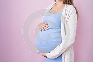 Young pregnant woman expecting a baby, touching pregnant belly scared and amazed with open mouth for surprise, disbelief face