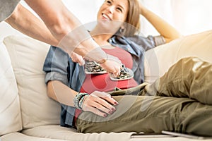 Young pregnant woman and future father playing with baby shoes up her belly - Happy family waiting for baby boy - Parenthood