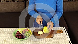 Young pregnant woman hands cut pear for fruit salad. Closeup