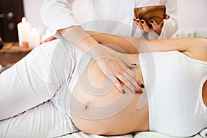 Young pregnant woman having abdominal massage at beauty spa salon. Close-up. Spa treatment