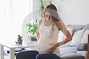 Young pregnant woman, having painful contraction, starting labor